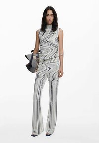 To-delt sæt i sort og hvid, med en ærmeløs top med høj hals og vide bukser med et swirlende mønster.