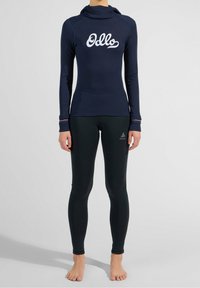 Marineblaue Langarmoberteil mit weißem "Odlo"-Logo, passende schwarze Leggings. Das Oberteil hat eine Kapuze und kontrastierende rote Akzente an den Bündchen.