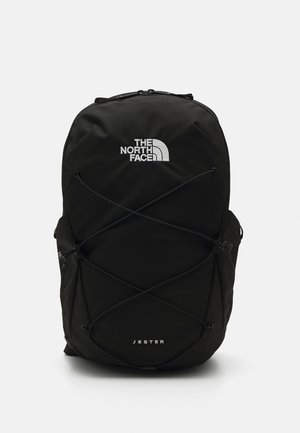 Mochila preta com o logótipo "THE NORTH FACE" na frente, apresentando um design de corda elástica, alças ajustáveis e uma textura de tecido resistente.