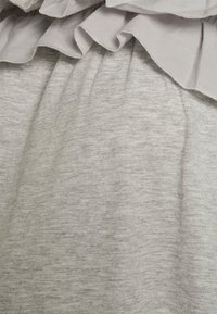 Tecido cinza com uma textura suave, com uma cintura franzida e uma renda decorativa ao longo da borda superior. Variações sutis de cor.