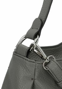 Borsa a mano in pelle grigia con una texture a granelli, dotata di hardware in metallo argentato e un design strutturato. Primo piano sul punto di attacco della tracolla e sui dettagli.