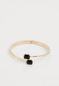 Pulsera de brazalete de oro con dos piedras preciosas negras rectangulares colocadas una enfrente de la otra en una banda abierta.