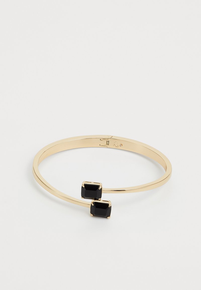 Pulsera de brazalete de oro con dos piedras preciosas negras rectangulares colocadas una enfrente de la otra en una banda abierta.
