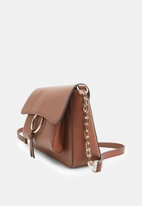 Borsa a tracolla in pelle marrone con chiusura a patta, dettagli in catena d'oro e un anello rotondo sul lato. Presenta una texture liscia e una forma ben definita.