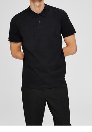 Camisa polo negra de algodón, con cuello clásico, tapeta de dos botones y mangas cortas. Combinada con pantalones negros.