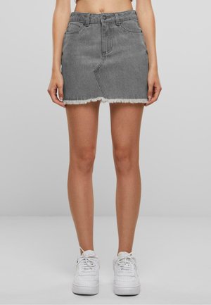Grå denim miniskjørt med flagrende kant, fem lommer og beltesløyfer. Kombinert med hvite joggesko.