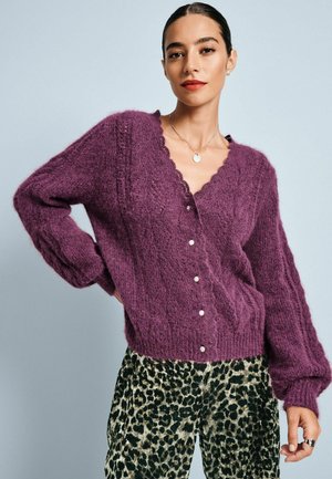 Purple, fluffy cardigan with a scalloped v-neckline and six white buttons, paired with leopard print pants featuring a soft texture.