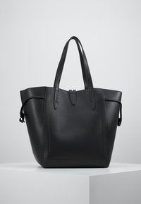 Czarna skórzana torba na ramię o teksturowym wykończeniu, z dwoma długimi uchwytami i minimalistycznym designem. Posiada zamknięcie górne oraz detale akcentujące po bokach.