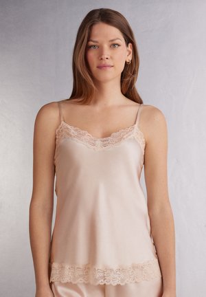 Silkes camisole i mjuk persika med spetskant längs halsringningen och fållen. Har tunna, justerbara axelband och en mjuk, lätt textur.
