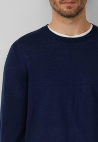Granatowy sweter z dzianiny z okrągłym dekoltem, z kontrastowym białym wewnętrznym kołnierzykiem i gładką fakturą, odpowiedni do codziennego noszenia.