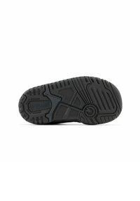 Semelle de chaussure de sport noire présentant une surface en caoutchouc texturé avec plusieurs rainures et motifs pour l'adhérence, marquée "New Balance".