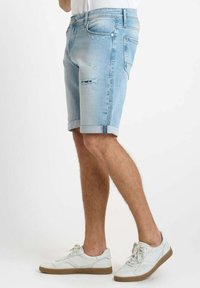 Pantalones cortos de mezclilla azul claro con detalles desgastados, dobladillo enrollado, cinco bolsillos y acentos de color en contraste en la cinturilla.