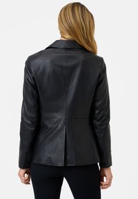 Black leather jacket with a fitted design, notched collar, and buttoned cuffs; smooth texture and seam detailing at the back.