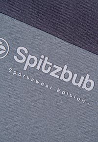 Das graue Sportbekleidungsgewebe hat eine glatte Textur, mit einem dunklen oberen Bereich. Fettes, weißes Text steht "Spitzbub Sportswear Edition."
