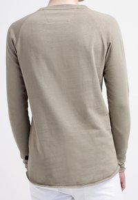 Langslevenshirt in lichtbruin, met een ronde halslijn en geribbelde textuur. Het ontwerp bevat raglanmouwen en een gebogen zoom.