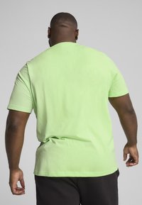 Tricou cu mânecă scurtă și guler rotund din bumbac verde lime strălucitor. Textură netedă, croială lejeră și culoare solidă, fără modele.