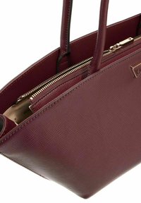 Sac à main bordeaux en matière texturée, avec des poignées doubles et un compartiment zippé. Présente un accent en métal doré à l'avant.