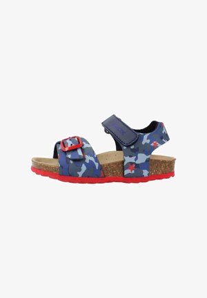 Sandales avec un motif camouflage bleu et des accents rouges, semelle en liège, sangle ajustable avec boucle rouge et semelle en caoutchouc texturée.
