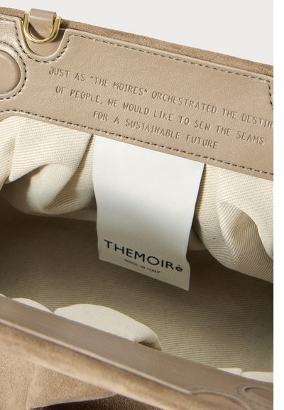Interno di una borsa in pelle che mostra un messaggio di sostenibilità in rilievo e un'etichetta in tessuto con il nome del marchio THEMoiré, realizzato in Italia.