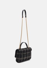 Sort tweed håndtaske med hvid rutemønster, guld kædetras, og kort sort læderhåndtag mod en enkel hvid baggrund.