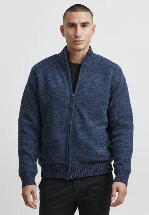 Navy blue zip-up sweater with a textured knit, ribbed cuffs, and waistband. Stand-up collar and side pockets add functionality.