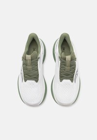 Baskets blanches avec des accents verts, en maille supérieure, col rembourré et semelle en caoutchouc. Présentent un design à lacets et un logo sur le côté.