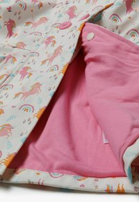 Waterproof jacket with a unicorn and rainbow print in pastel colors; features a pink cotton lining and snap-button closure.