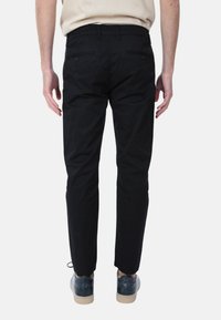 Chino neri con vestibilità slim, con fronte piatto, passanti per cintura e tasche posteriori. Abbinati a scarpe blu, creano un look pulito.