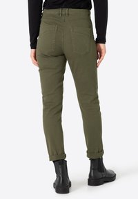 Olijfgroene, slimfit broek van een gladde stof, met een middelhoge taille, opgerolde mouwen en vier zakken. Gemaakt met zwarte enkelboots.