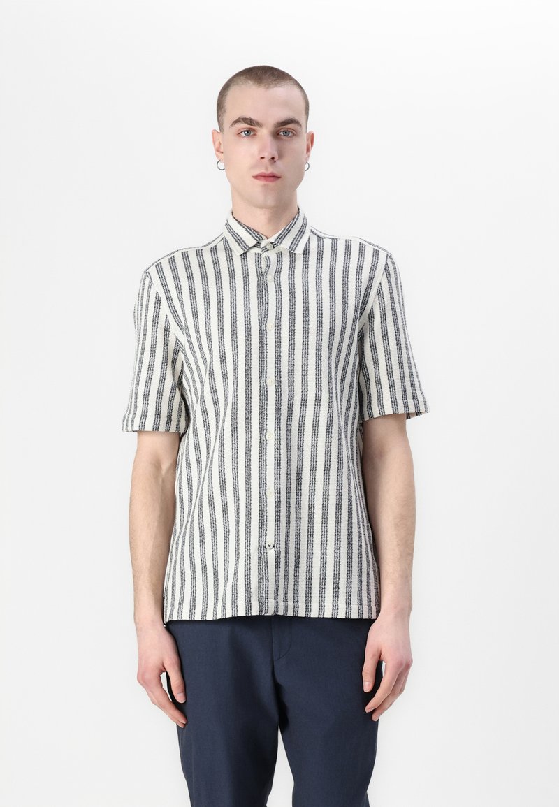 Camicia a maniche corte con bottoni, a strisce verticali bianche e nere, realizzata in tessuto leggero, con colletto classico e orlo dritto.