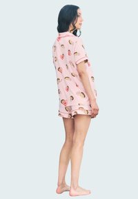 Conjunto de pijama rosa con una camiseta de manga corta y pantalones cortos, con un patrón de erizo y corazones. La tela parece suave y ligera.