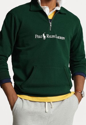 Grüner Quarter-Zip-Sweatshirt mit erhöhtem Kragen und Taschen auf der Vorderseite. Mit weißem "Polo Ralph Lauren"-Logo und darunterliegenden, geschichteten gelben und marineblauen Designs.