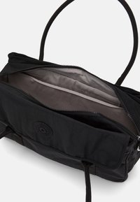 Black fabric bag with a zippered closure, dual rope handles, and a logo patch. Interior features a smooth, dark lining with no compartments.