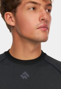 Czarny sportowy sweter z okrągłym dekoltem, fakturowana tkanina i dyskretne logo na klatce piersiowej. Posiada kontrastowe przeszycia.