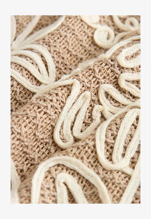 Gestickter Stoff in Beige mit cremefarbener Fadengestaltung, die komplexe Wirbel bildet und eine strukturierte, gewebte Oberfläche zeigt.