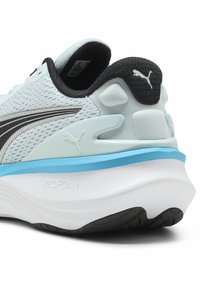 Világoskék futócipő, hálós felsőrésszel, fekete részletekkel, ezüst csíkkal és vastag fehér középtalppal, melyen a "PROFOAM" felirat olvasható. Mintás talppal rendelkezik.