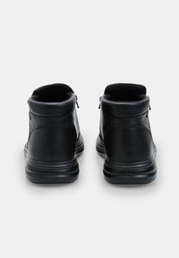 Botas de tobillo de cuero negro con un acabado suave, cuello acolchado y una suela de goma de perfil bajo. Cremalleras traseras para una fácil colocación.