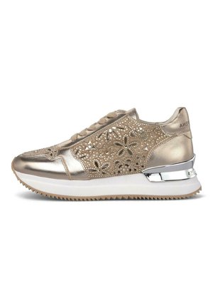 Zapatilla deportiva dorada metálica con diseño de recortes florales, cordones delanteros, suela plataforma blanca y detalle plateado en el talón sobre una suela de goma estriada.