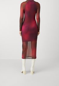 Rot schwarze Ombre-Mesh-Kleid mit langen Ärmeln, eleganter Silhouette und Midi-Länge, kombiniert mit weißen Blockabsatzstiefeln.