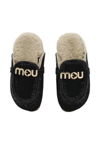 Pantofole nere in suede con fodera in shearling beige, logo centrale dorato e cuciture decorative lungo i bordi.