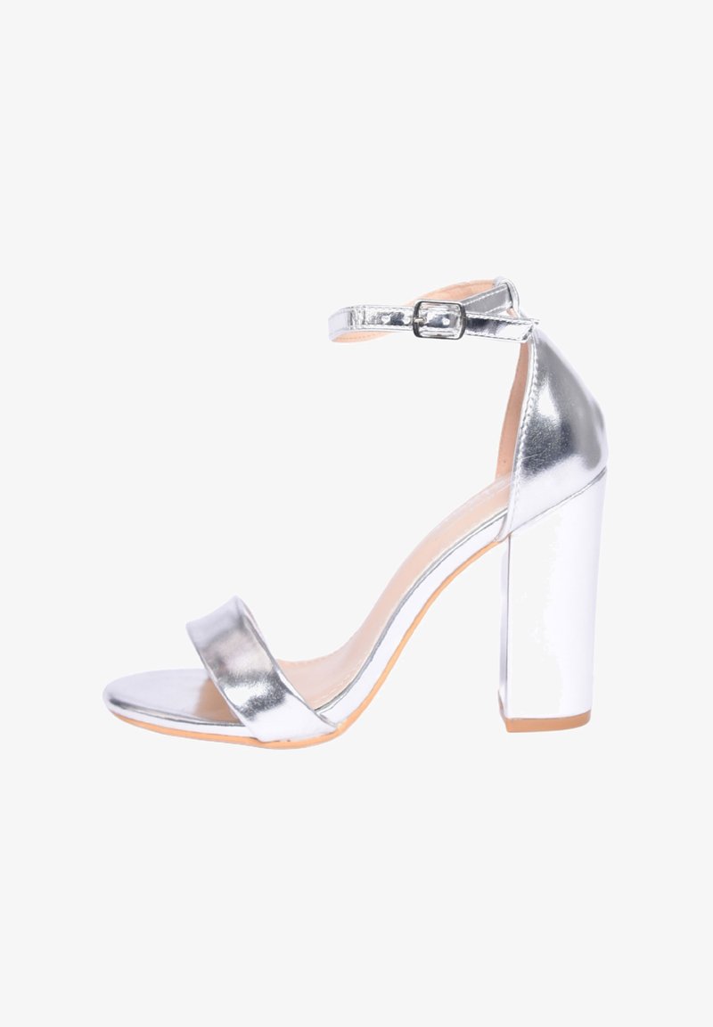 Sandalo argenteo con tacco grosso a blocco, cinturino alla caviglia e una texture metallica liscia. Design open toe con cinturini minimi.