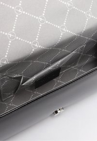 Interno di una borsa a mano nera in pelle, caratterizzato da un tessuto grigio con un motivo geometrico bianco, una tasca a soffietto e una chiusura in metallo argentato.