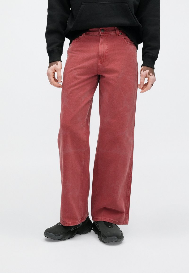 Red wide-leg jeans made of denim, featuring a classic button and zipper closure, two front pockets, and a faded texture.