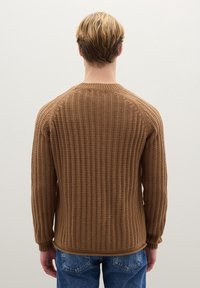 Bruine geribbelde gebreide trui met lange mouwen en ronde hals, gezien van achteren. Gecombineerd met blauwe spijkerbroek.