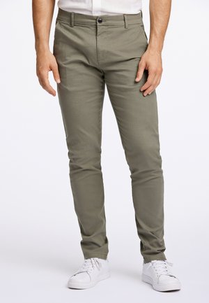 Chinos slim fit en olive en tissu mélangé coton, dotés d'une fermeture à bouton, de poches latérales, et d'une couture assortie avec des baskets blanches.