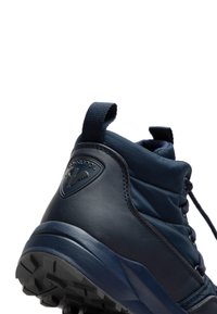 Zapatillas altas de color azul marino hechas de material sintético texturizado. Presentan un logo en el talón, suela texturizada y un tira en el empeine para facilitar su uso.