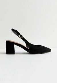 Scarpa con tacco alto in suede nero, con punta chiusa, tacco a blocco angolare e cinturino alla caviglia regolabile con una piccola fibbia metallica.