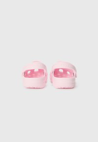 Pink rubber sandals with open back and dual side ventilation holes. The footbed is textured, and the brand name is embossed on the strap.