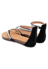 Schwarze Wildleder-Sandalen mit Strass-Akzenten, Reißverschluss an der Ferse, Korkfußbett und flacher Gummisohle. Offene Zehen und überkreuzte Riemen.