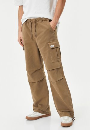 Khaki cargobroeken met een elastische tailleband, twee zijzakken en twee grote dijzakken. Gemaakt van duurzaam katoen.